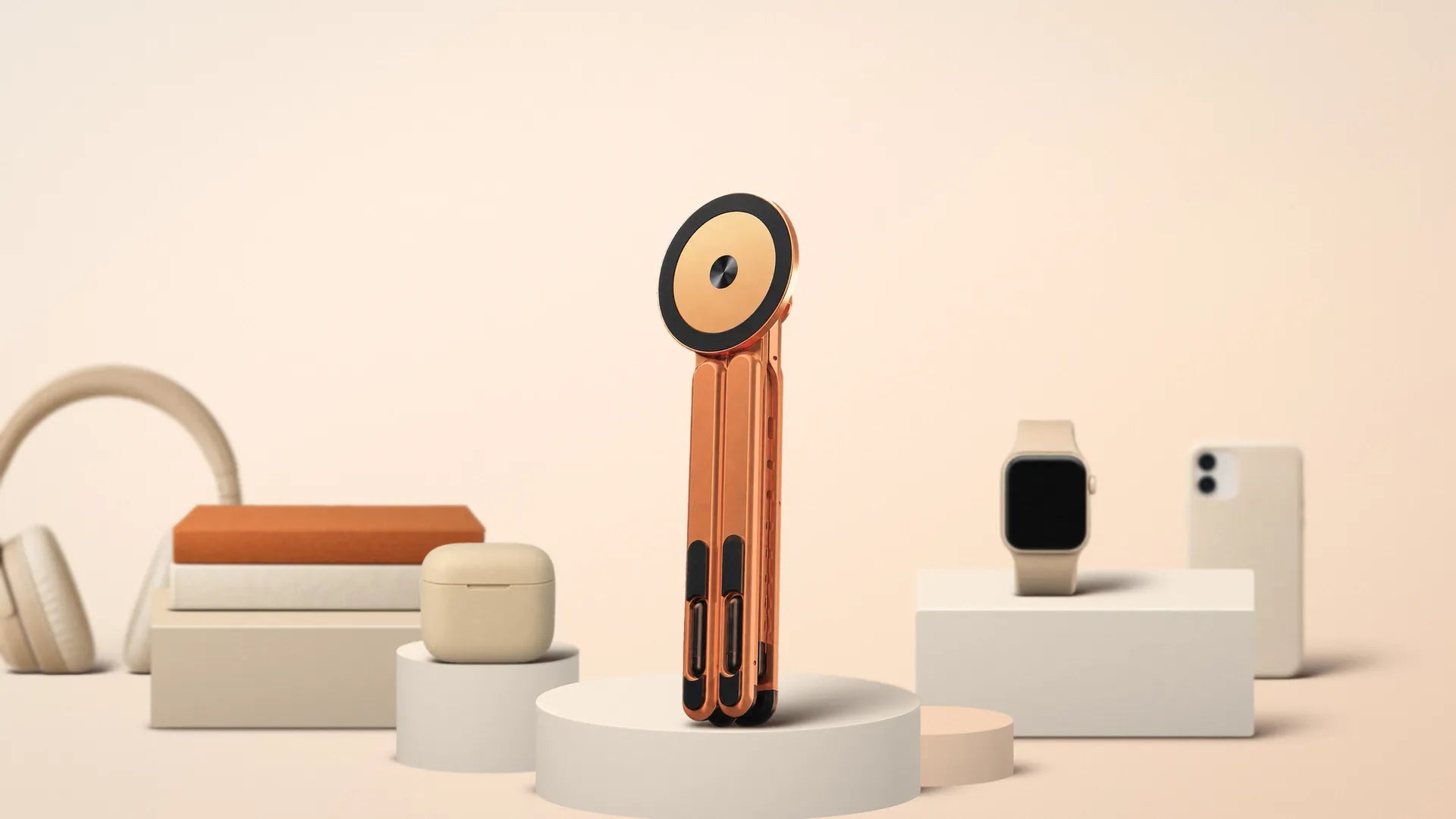 Vante Polaris naranja plegado, de pie sobre un podio, entre unos cascos, unos libros, un estuche de auriculares, un reloj y un móvil en tonos crema y arena
