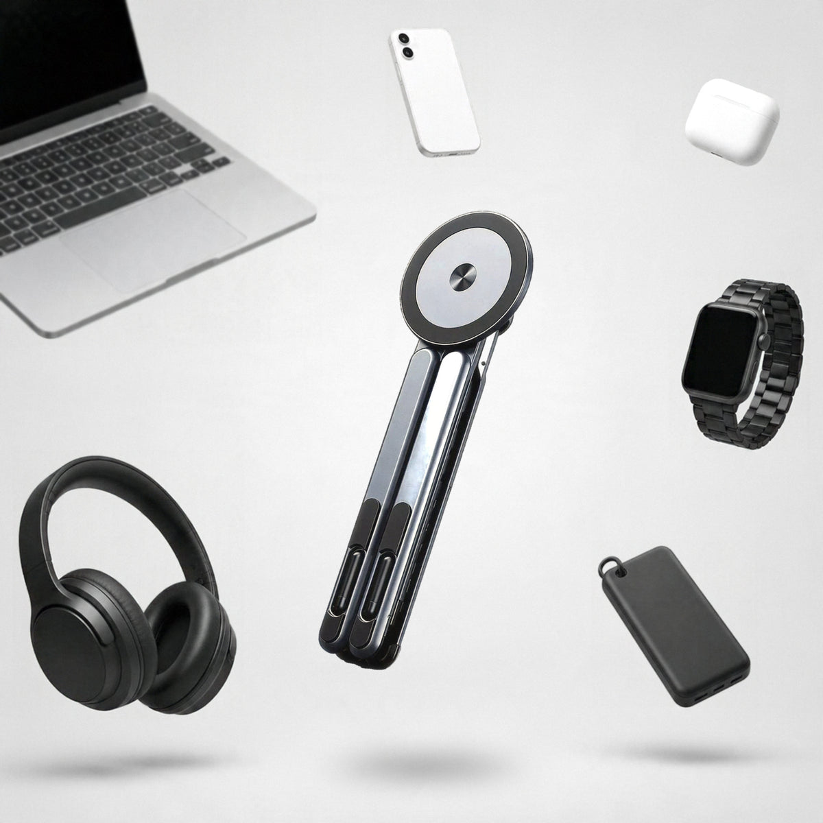 Vante Polaris gris plegado flotando en un estudio claro entre un portátil, un móvil, unos auriculares, un reloj, unos cascos y una batería