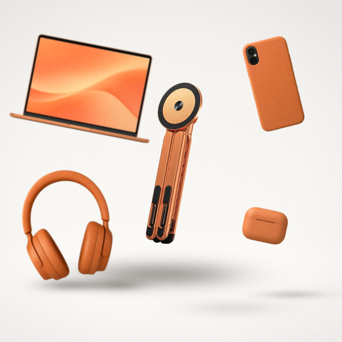 Vante Polaris naranja plegado flotando en un estudio blanco entre un portátil, un móvil, unos cascos y un estuche de auriculares, todos naranjas